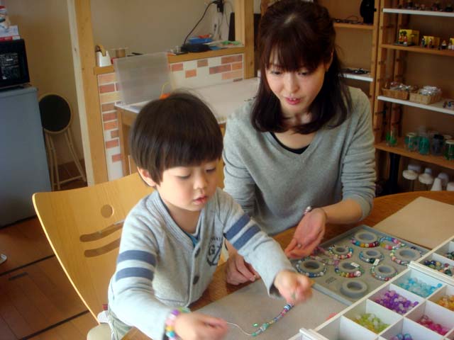 ゴム紐にビーズやとんぼ玉を通しています