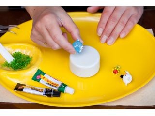 白台座のオルゴールにガラスの砂とガラスのミニチュアをボンド付けします。スタッフがボンドが固まるまでお預かりして、30分後にお渡しできます。