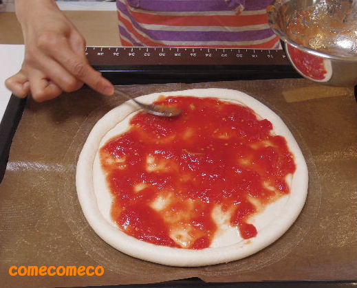 トマトたっぷりのピザソースを生地に塗って