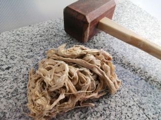 御影石の台の上で、コウゾの原料を木槌で丹念に叩きます。