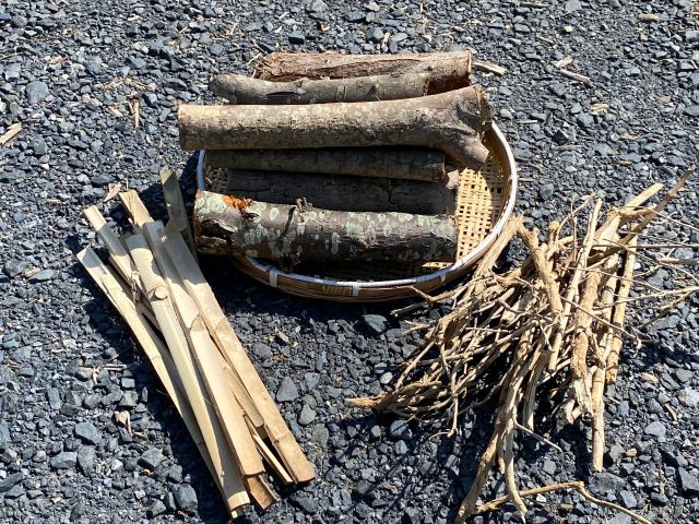 燃料として薪10キロ(写真奥)ならびに焚き付けの竹(写真左手前)と紫陽花の枝(写真右手前)を無料で提供します。