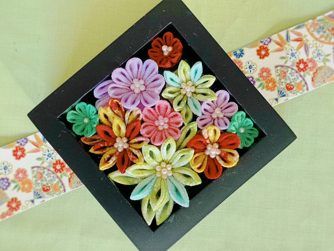 パズルのように隙間なく、つまみ細工を箱枠に敷き詰めて、花溢れる感じに仕上げます