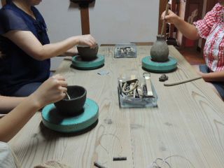 手回しロクロで器をつくっている親子。