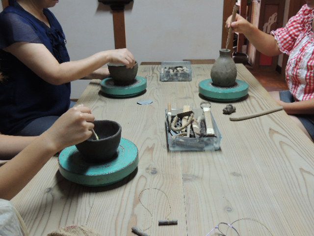手回しロクロで器をつくっている親子。