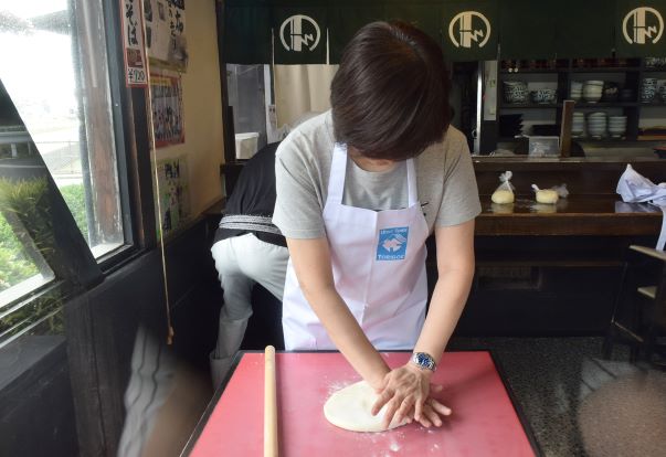 手のひらと麺棒を使ってうどん生地を伸ばします