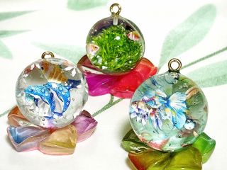 透明なレジンに金魚やイルカ、水草を閉じ込めた幻想的なアートチャーム。まるで小さな水族館のような世界を楽しめます。