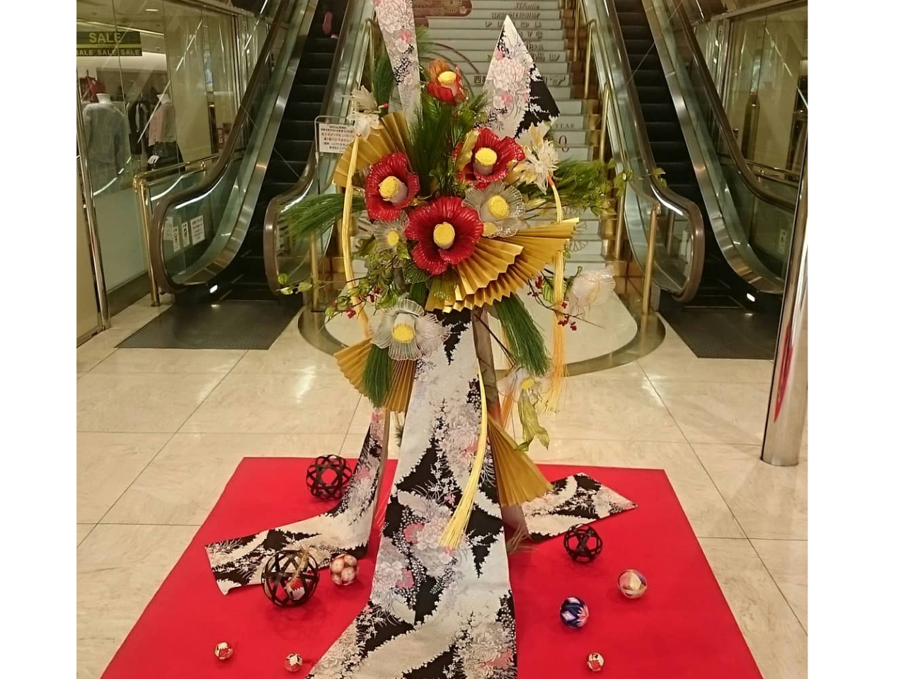 お店のディスプレイをさせていただいたときの正月アレンジです。アメリカンフラワーで顔くらいの大きな椿を制作し着物と和風に仕上げしました。