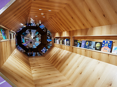 八角形のどうくつ型図書館には、美しい図鑑や写真集・海外の絵本など、ふだん子どもがあまり目にすることのない本がズラリと並びます。奥には鏡の万華鏡も