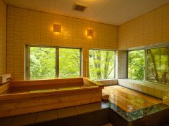 窓の外には森の緑が広がる本館の檜の湯。檜の香りが情緒たっぷりのひと時を叶えてくれる。