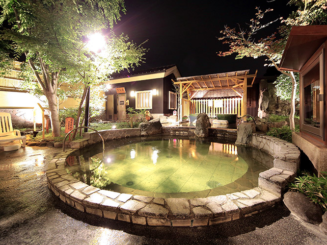 〈野天岩風呂(源泉加温循環)〉 皆様で語らっていただける、まんまるのお風呂です。温泉成分の力で身体の芯から温まります。