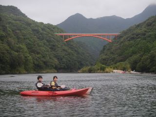 the安房川の景色、赤い松峰大橋と照葉樹林と