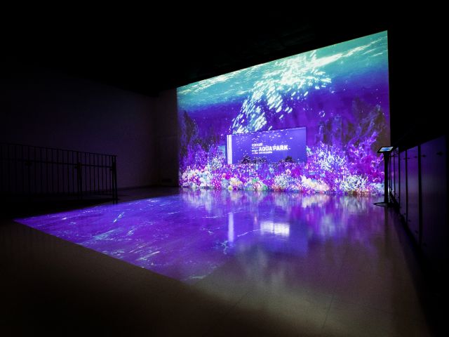 〜パークエントランス〜魚たちや映像などがゲストをお出迎え。マクセルの虹色に輝く魚群と水槽に投射された美しい映像、洗練されたアートワークがコラボレーションを象徴。