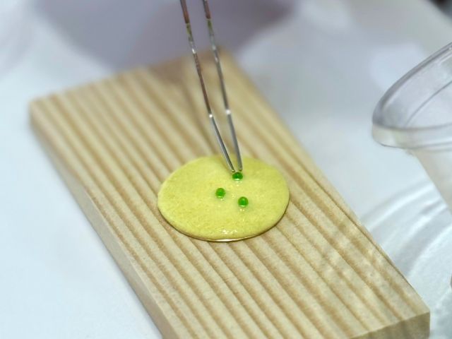 作業風景例:銅板の土台に釉薬をのせてビーズで飾り付けていきます。