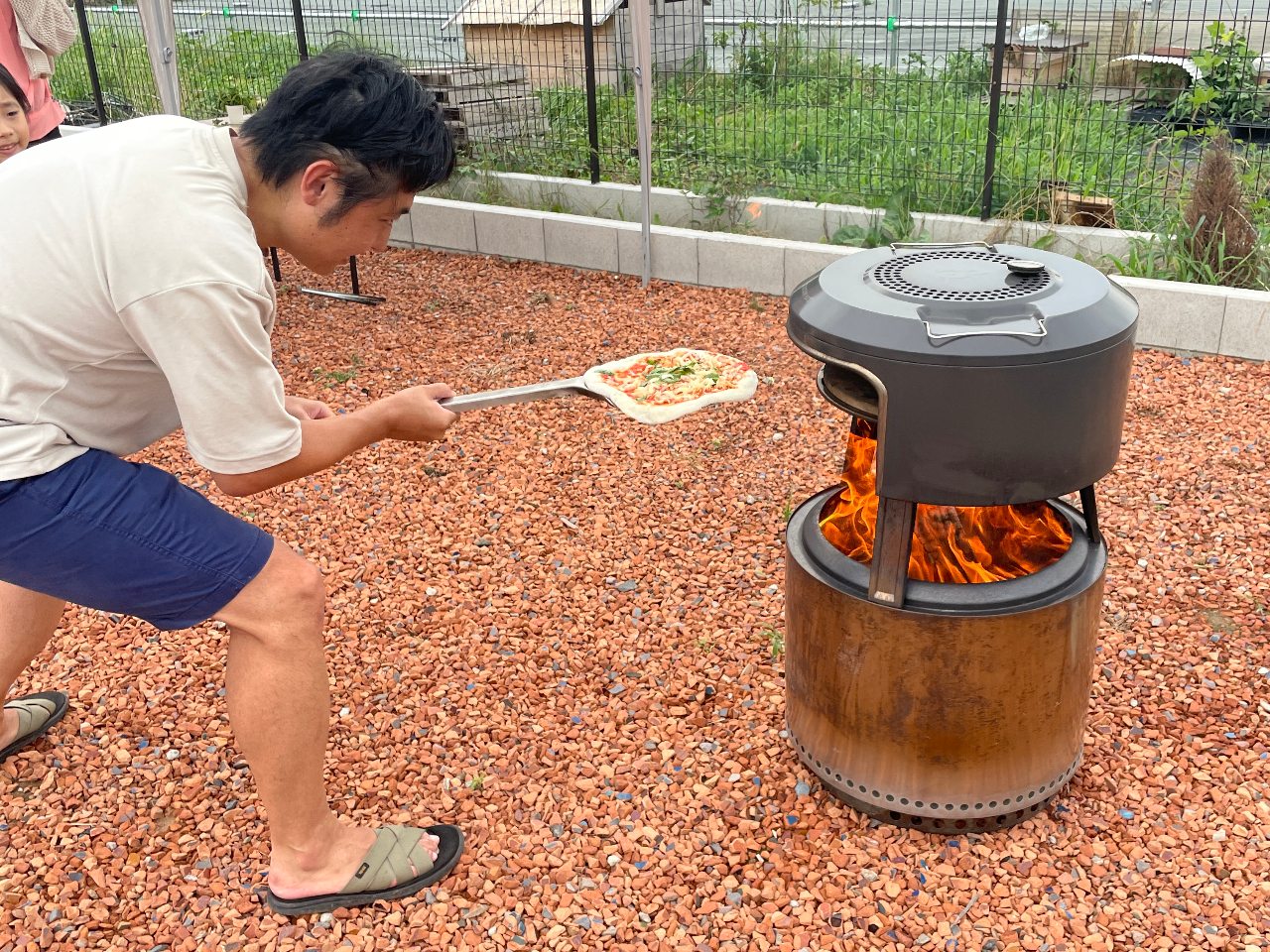 ピザ釜にピザを投入して、焚き火でピザを焼いていただきます。およそ7分程度で焼けます!
