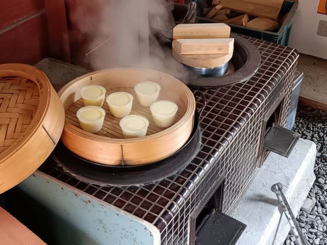 かまどで薪を燃やして蒸しプリンを作ります。ご飯炊きと同時進行です。