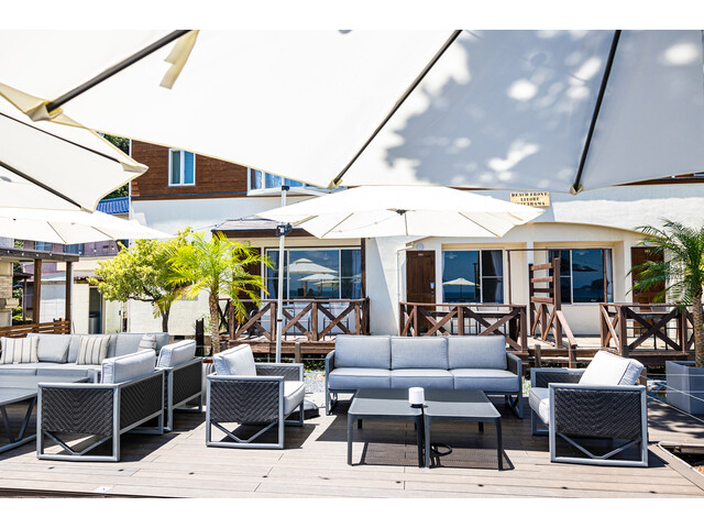 ウッドデッキに並ぶ広々としたソファー席。映える白いパラソルで南国気分。