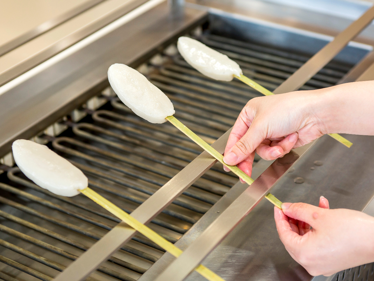 【体験】串に刺したかまぼこを、焼き炉に立てかけます。