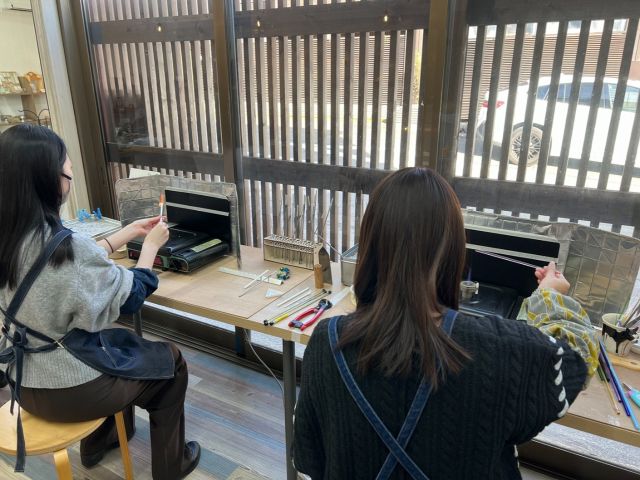 とんぼ玉体験の様子です。エプロンとアームカバーを着けて作業をして頂きます。