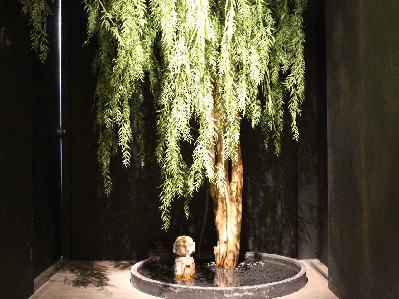 エントランス内を少しだけお見せします。。柳の木から滴り落ちる水が、池の中のお地蔵様をつたいます。