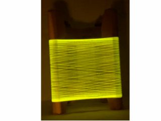 座繰り器を用いて、蛍光繭から巻き取った糸を光らせて観察しているところです。